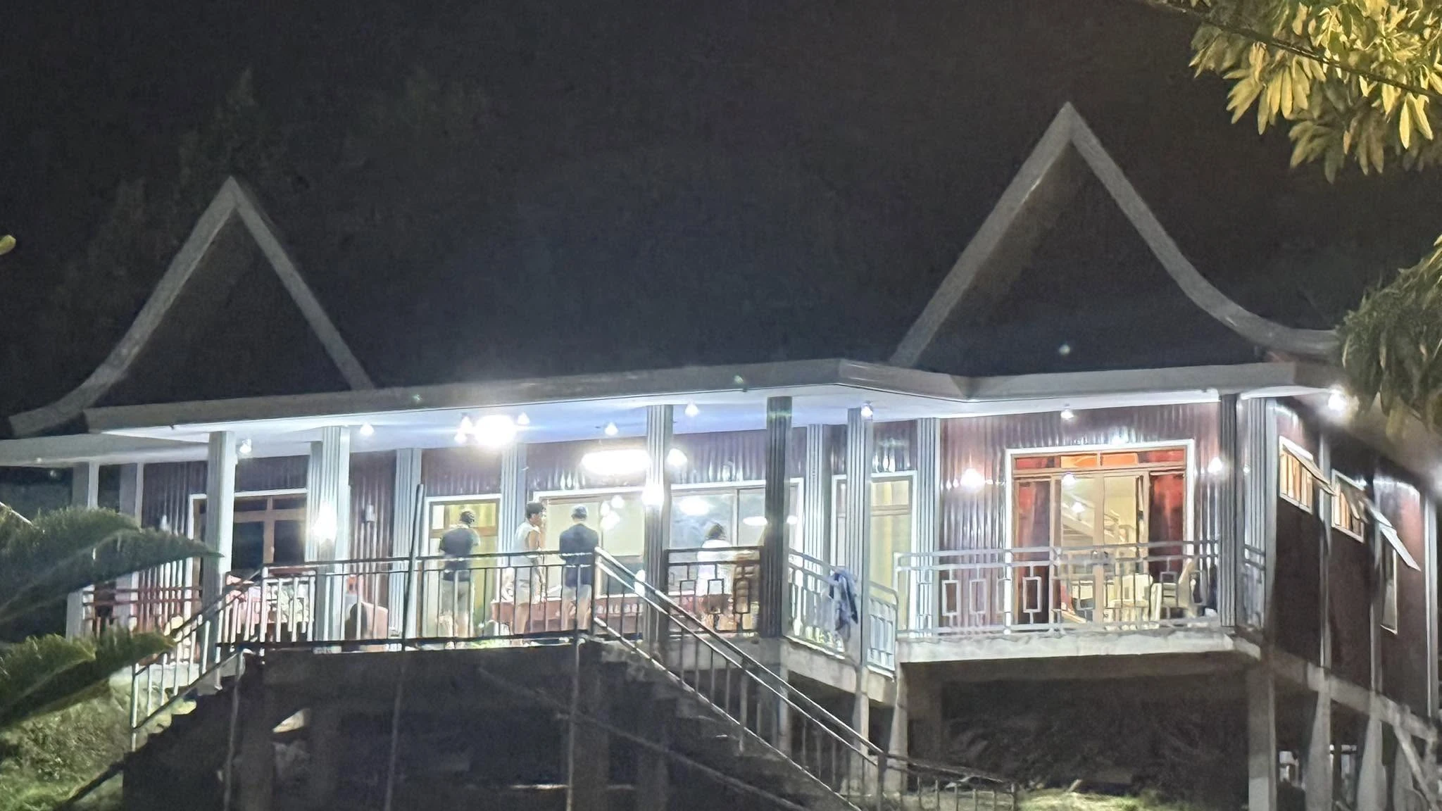Illuminated glass-front accommodation building and veranda at Odyson’s Mountain Resort at night