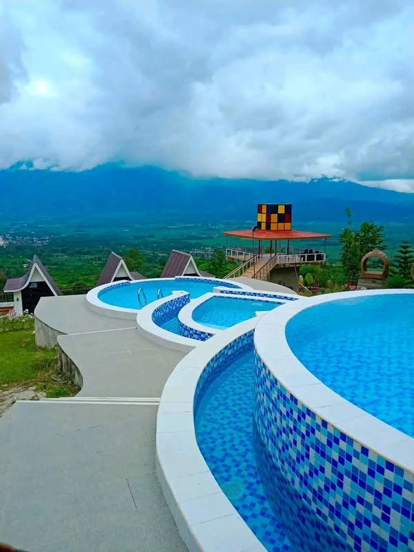 Blue swimming pools, A-frame rooftops and a cloud-filled valley at Odyson’s Mountain Resort