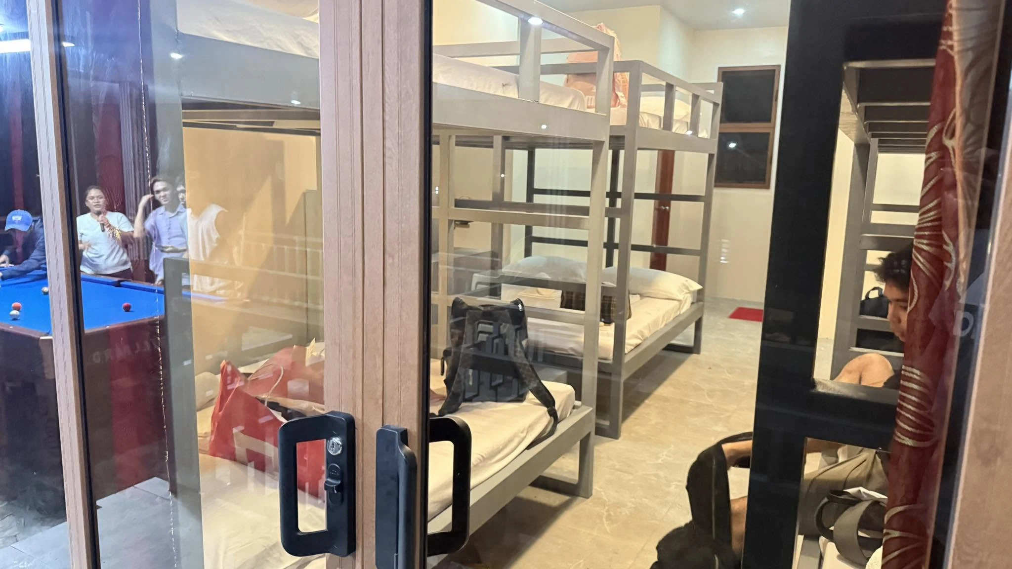 Bunk beds and the interior of an accommodation room seen through its glass doorway at Odyson’s